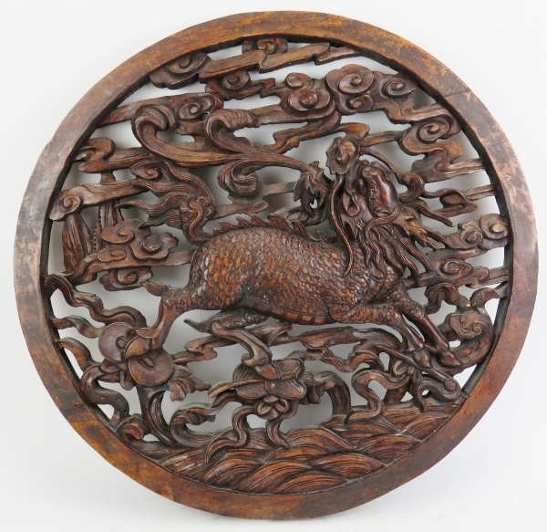 A large Chinese carved wood roundel, 20th century. Carved in openwork depicting a dragon amongst