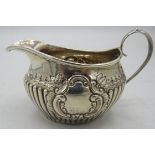 A small silver cream jug with 1/2 fluting and embossed decoration, silver marks worn. Approx