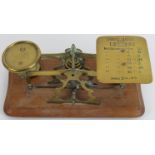 A set of brass postal scales and weights. One tray inscribed with a postal rates list for letters.