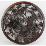A large Chinese carved wood roundel, 20th century. Carved in openwork depicting a peacock amongst
