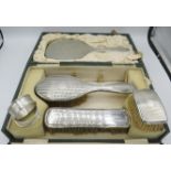 A three piece silver dressing table set comprising of hand mirror, hair brush and clothes brush,