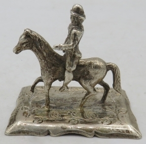 A white metal figure of a man riding a horse, marks to base, possibly Dutch. Approx 2"/5cm high