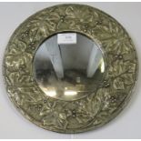 A small circular Arts & Crafts wall mirror in a repousse pewter surround depicting fruiting vines.