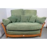 A contemporary ash two-seater sofa by Ercol, with loose cushions in green and matching scatter