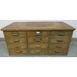 A 1930s oak bank of 12 short drawers with bar handles. H44cm W96cm D48cm (approx). Condition report: