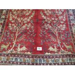 A North East Persian meshed carpet central scene of trees, stage and birds on red ground. In good