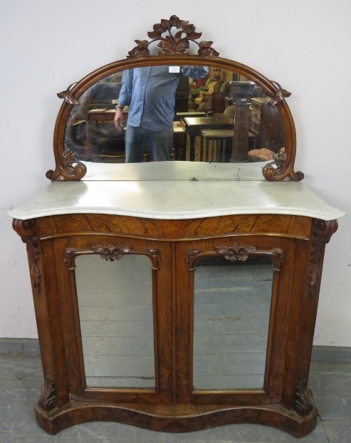 A Victorian walnut serpentine fronted chiffonier, the mirror back with foliate carved cornice and