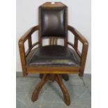 An Edwardian walnut swivel height adjustable captain’s desk chair, upholstered in black leather with