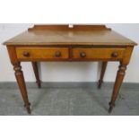 A Victorian walnut writing table with rear gallery, housing two short drawers with turned wooden