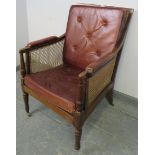 A Regency Period bergère library chair, with loose cushions upholstered in oxblood buttoned leather
