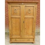 An antique Continental pine double wardrobe, the panelled doors opening onto a loose shelf above a