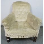 A Victorian armchair, upholstered in cream buttoned velvet material with brass studs, on turned