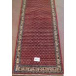 North East Persian Mir runner central repeat pattern field on red ground and in good condition. 3.80