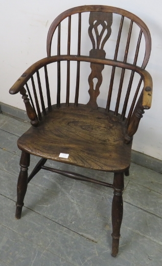 An early 19th century elm and yew wood Windsor hoop-back chair, on turned canted supports with an ‘