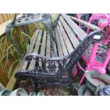 A vintage wrought iron scroll back garden bench with pierced end supports and teak slatted seat.