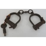 A pair of cast iron handcuff shackles, probably 19th century. Condition report: Some wear with age.