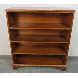 A reproduction Yew wood open bookcase, crossbanded and strung with ebony, housing three height-