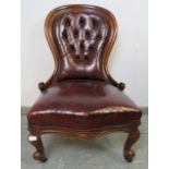 A Victorian mahogany spoonback armchair, upholstered in buttoned burgundy leather with brass