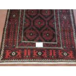 A North East Persian meshed Belouch rug deep burgundy high lighted with black and white. In good