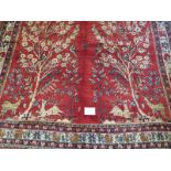 A North East Persian meshed carpet central scene of trees, stage and birds on red ground. In good