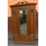 An Edwardian lightwood double wardrobe with scrolled pediment, the front with carved and fielded