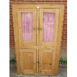 An antique stripped pine pantry cupboard, the top section with glazed doors opening onto two