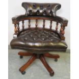 An antique style mahogany captain’s height adjustable swivel desk chair, upholstered in buttoned