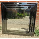 A large square contemporary bevelled wall mirror, in a sectioned and bevelled smoked glass surround.