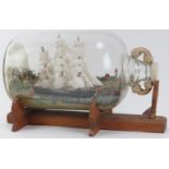 A large vintage model of a schooner ship in a bottle. Modelled with a three mast schooner in a