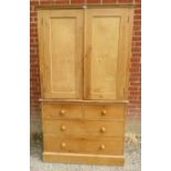 An antique pine linen press, the doors opening onto twin hanging rails, the base section with two