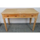 An antique stripped pine side table, housing two short drawers with turned wooden handles, on