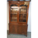 An antique flame mahogany tall glazed bookcase, the tracery doors opening onto three height