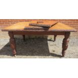 A Victorian medium oak wind-out extending dining table with two individually leaves