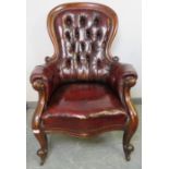 A Victorian mahogany spoonback armchair, upholstered in buttoned burgundy leather with brass