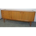 A mid-century teak sideboard by Waring & Gillow, housing four short drawers, one with cutlery