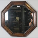 An early 20th century octagonal bevelled wall mirror in an oak surround with braided rope edge