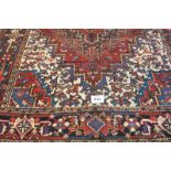 North West Persian Heriz carpet central large motif fanning out on a red ground with blue, white and