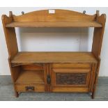 An Arts & Crafts Period light oak wall hanging shelf with single cupboard under and one small oak