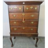 An 18th century oak chest on stand, housing two short over three long drawers with fancy brass