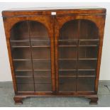 A Georgian style walnut low glazed bookcase, the doors opening onto two height adjustable loose