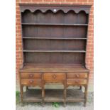 An 18th century oak Welsh dresser, the top with arcaded canopy above three open shelves, the base