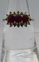 A 9ct yellow gold three stone ruby and diamond cluster ring. Approx .06ct diamonds. Size N.