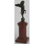 A European bronze figure of cupid holding a bow, 19th century. Supported in a rouge griotte marble