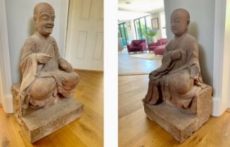 A large architectural pair of Chinese carved red sandstone Luohan guardian monk temple figures.