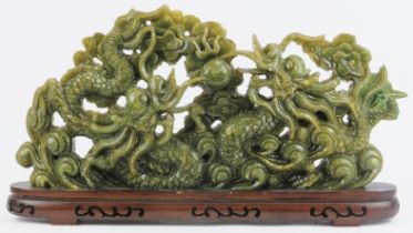 A large Chinese green hardstone carving of two dragons confronting a flaming pearl amongst clouds