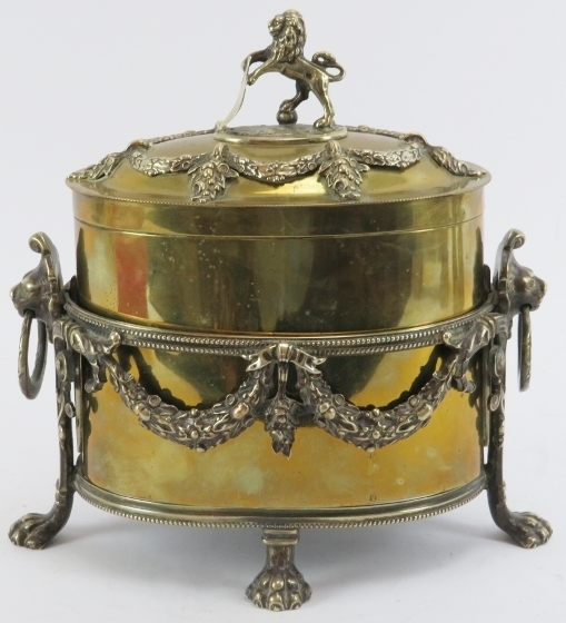 A brass tea caddy with plated silver mounts and stand, 19th century. The hinged brass cover