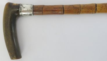 An antique rhinoceros horn handled and silver collared bamboo walking cane, early 20th century. With