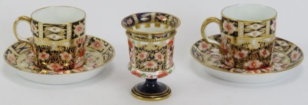 Two Royal Crown Derby coffee cups and saucers and a miniature urn decorated in the Imari palette.