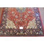 A Persian Sarough rug, central blue motif on red ground and in good condition. 210cm x 142cm.