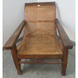 A turn of the century colonial teak plantation chair, with bergère seat, the arms with fold-out